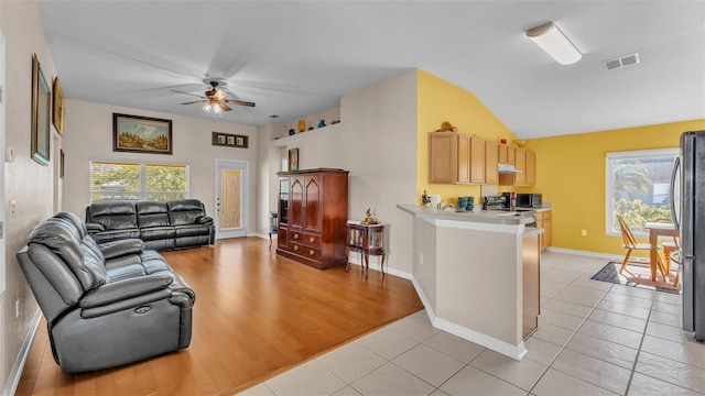 living room with ceiling fan, light hardwood / wood-style floors, and lofted ceiling