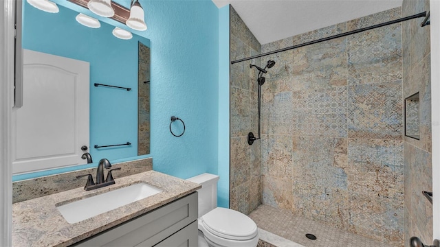 bathroom with vanity, toilet, and tiled shower