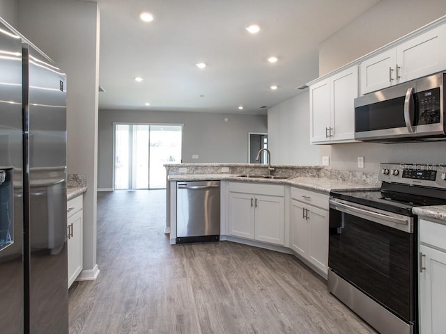 kitchen featuring appliances with stainless steel finishes, light stone counters, sink, light hardwood / wood-style floors, and white cabinetry