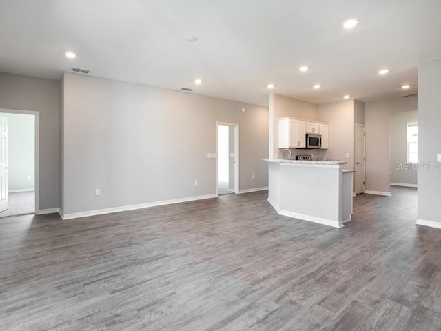 kitchen with white cabinets, dark hardwood / wood-style floors, and a center island with sink