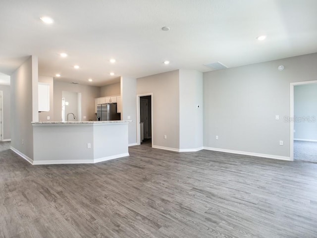 unfurnished living room featuring hardwood / wood-style floors and sink