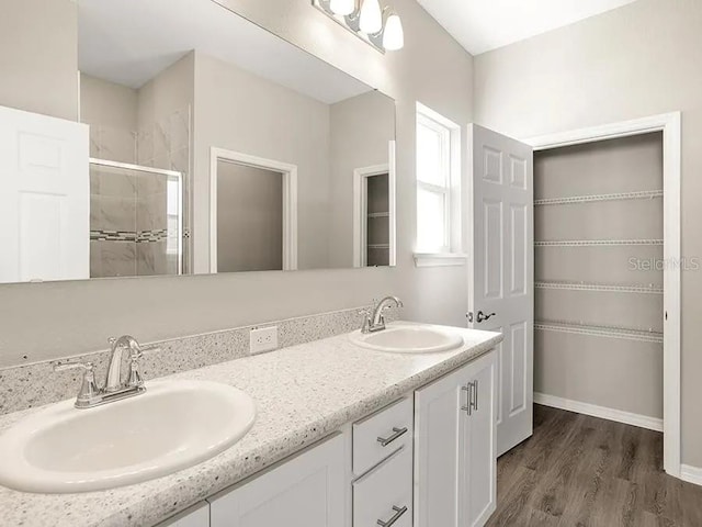 full bath with double vanity, wood finished floors, a stall shower, and a sink