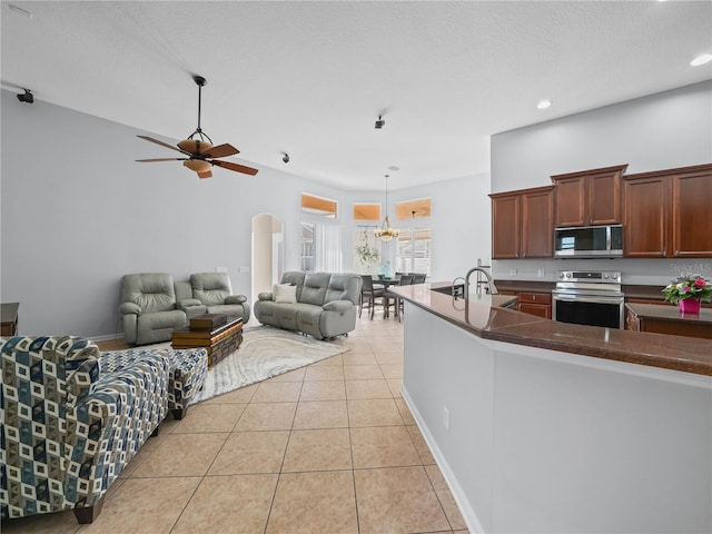 kitchen featuring hanging light fixtures, a textured ceiling, light tile patterned floors, ceiling fan with notable chandelier, and appliances with stainless steel finishes