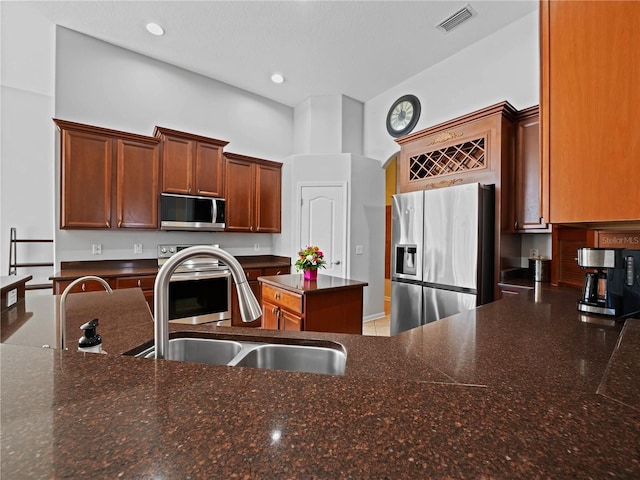 kitchen featuring sink, dark stone counters, and appliances with stainless steel finishes