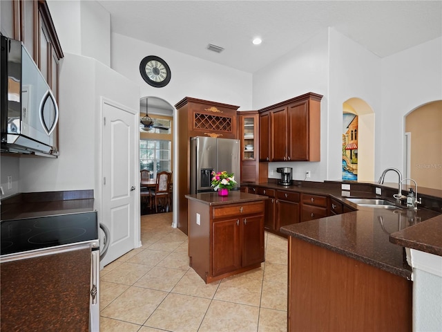 kitchen featuring sink, stainless steel appliances, light tile patterned floors, kitchen peninsula, and a kitchen island