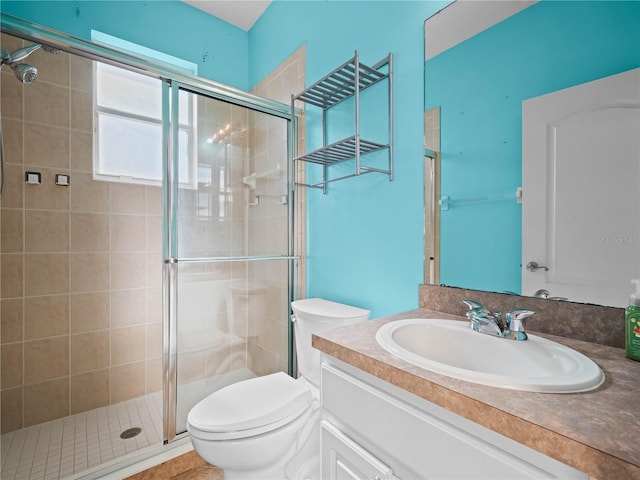 bathroom featuring vanity, toilet, and a shower with shower door