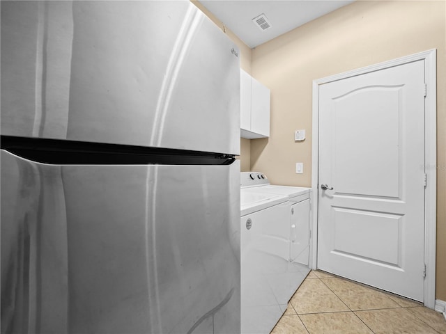 laundry area with washer and clothes dryer, cabinets, and light tile patterned floors