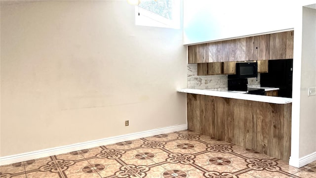 kitchen featuring kitchen peninsula, backsplash, and black appliances