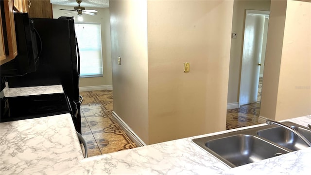 kitchen with black refrigerator, sink, ceiling fan, and stove