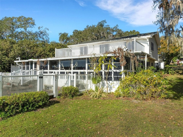 rear view of property featuring a sunroom and a yard