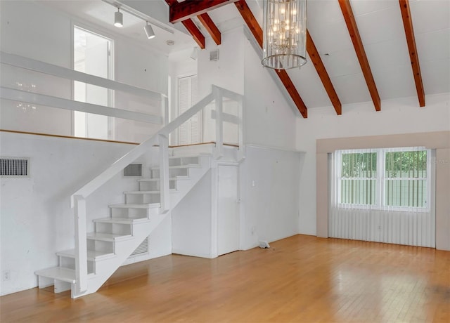 unfurnished living room featuring a notable chandelier, wood-type flooring, and high vaulted ceiling