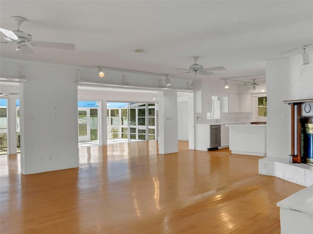 unfurnished living room with sink, rail lighting, and light hardwood / wood-style floors