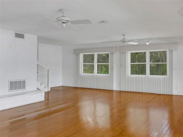 unfurnished living room with a textured ceiling, hardwood / wood-style flooring, and ceiling fan