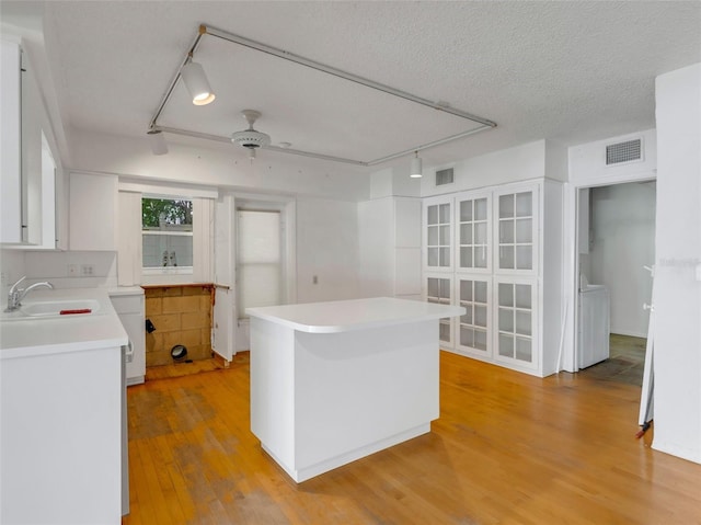 kitchen featuring a textured ceiling, ceiling fan, sink, light hardwood / wood-style flooring, and white cabinetry