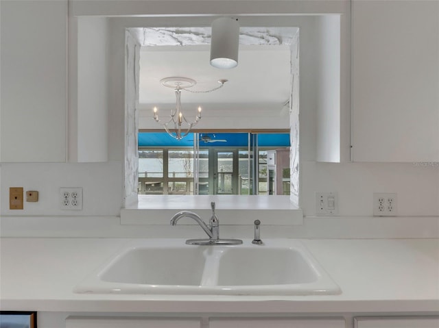 kitchen with white cabinetry, sink, and an inviting chandelier