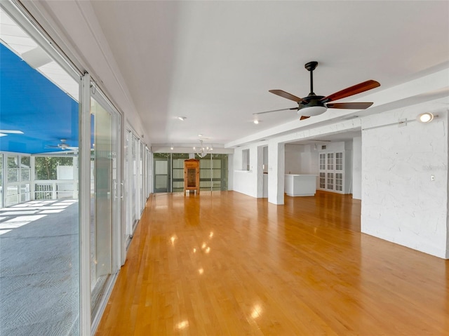 interior space with ceiling fan with notable chandelier and hardwood / wood-style flooring