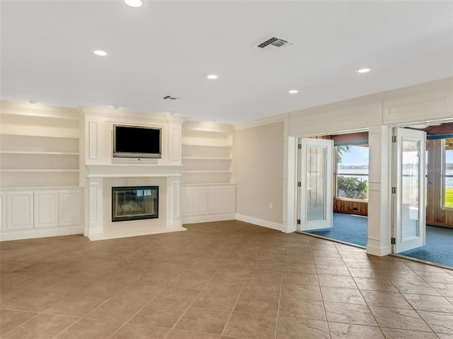 unfurnished living room with built in shelves, ornamental molding, and light tile patterned flooring