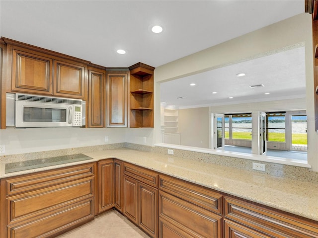 kitchen with light stone countertops, light tile patterned floors, black electric cooktop, and kitchen peninsula