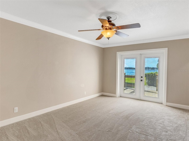 carpeted spare room featuring french doors, ceiling fan, and crown molding