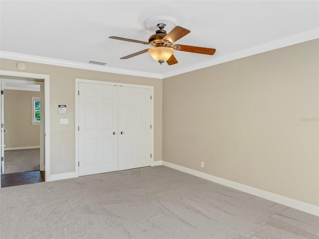 unfurnished bedroom with ceiling fan, a closet, light colored carpet, and ornamental molding