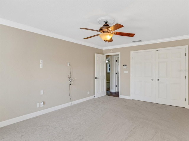 unfurnished bedroom with carpet flooring, a closet, ceiling fan, and crown molding