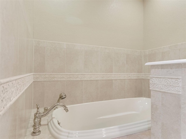 bathroom featuring tile patterned floors, a tub, and tile walls