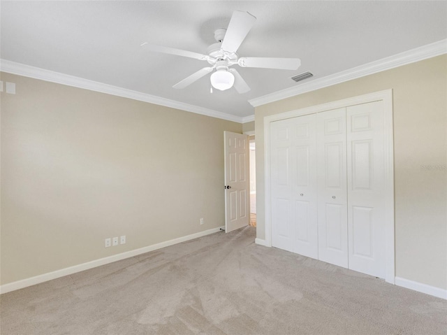 unfurnished bedroom with ceiling fan, light colored carpet, ornamental molding, and a closet