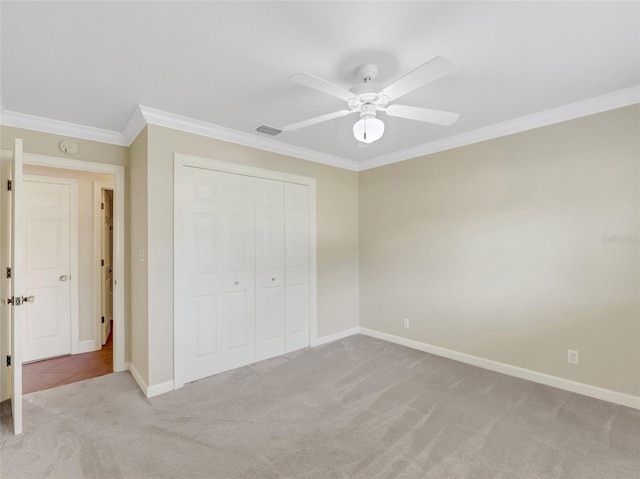 unfurnished bedroom featuring ceiling fan, crown molding, light carpet, and a closet