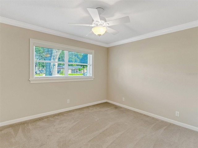 spare room with ceiling fan, crown molding, and light carpet