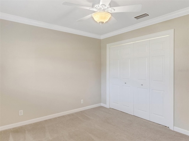 unfurnished bedroom featuring light carpet, a closet, ceiling fan, and crown molding