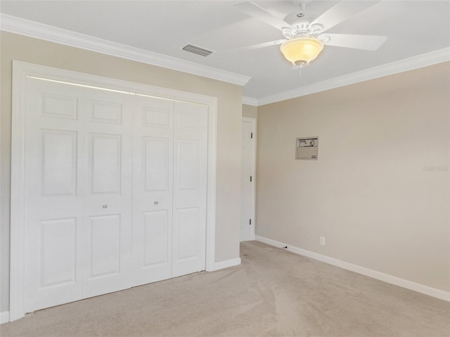 unfurnished bedroom with crown molding, ceiling fan, a closet, and light colored carpet