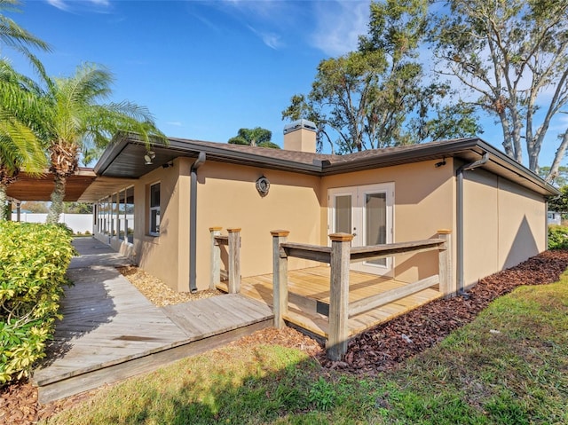 rear view of property featuring a deck and french doors