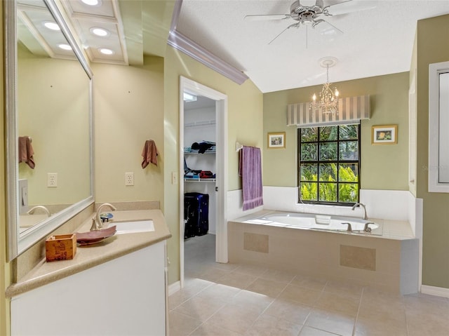 bathroom with tile patterned flooring, a relaxing tiled tub, a textured ceiling, vanity, and ceiling fan with notable chandelier