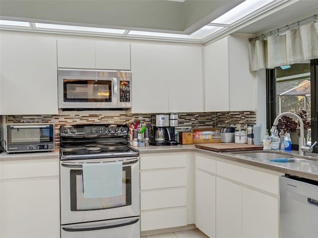 kitchen with backsplash, white cabinetry, sink, and appliances with stainless steel finishes