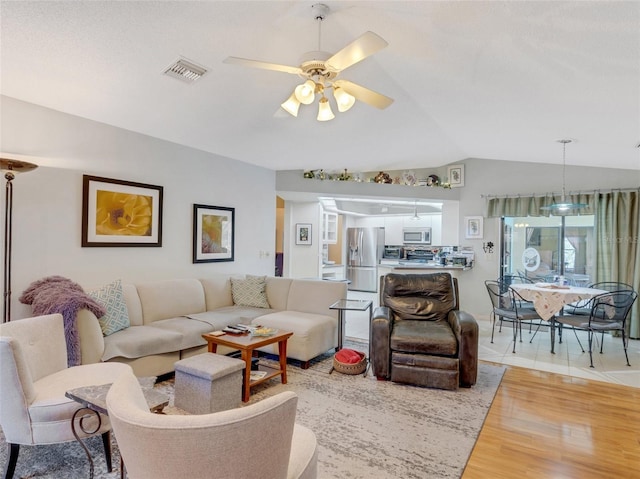 living room with hardwood / wood-style flooring, ceiling fan, and lofted ceiling