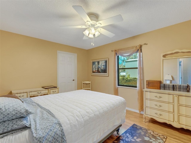 bedroom featuring a textured ceiling, light hardwood / wood-style floors, and ceiling fan