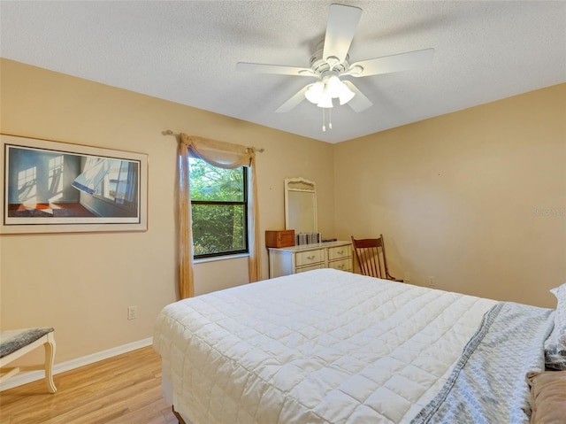 bedroom featuring ceiling fan, light wood-type flooring, and a textured ceiling