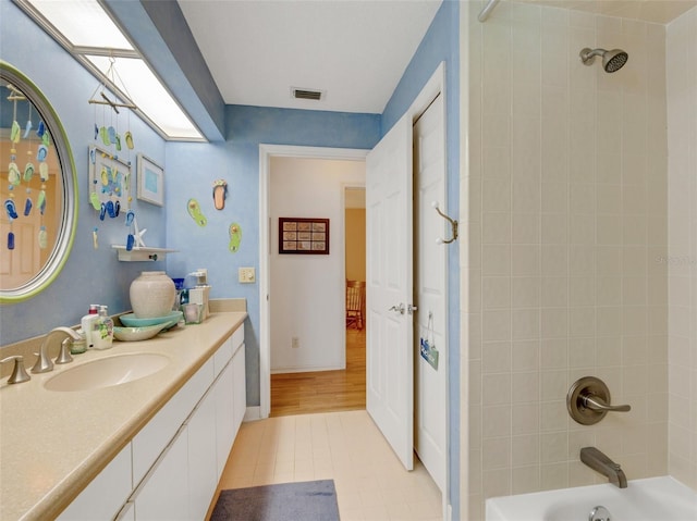 bathroom with wood-type flooring, vanity, and tiled shower / bath