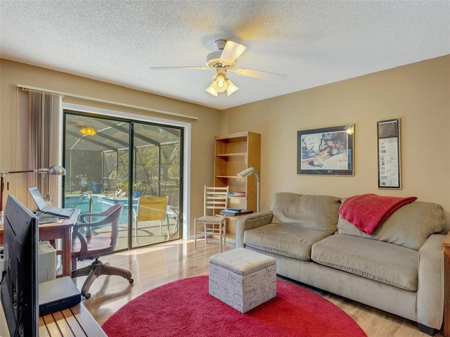 living room featuring ceiling fan, light hardwood / wood-style floors, and a textured ceiling