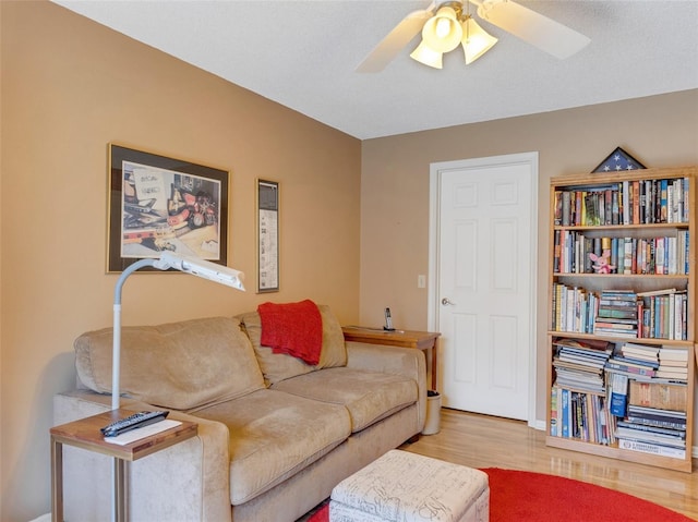 living room featuring ceiling fan, light wood-type flooring, and a textured ceiling