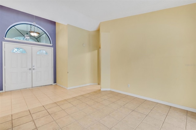 foyer entrance with light tile patterned flooring, vaulted ceiling, and baseboards