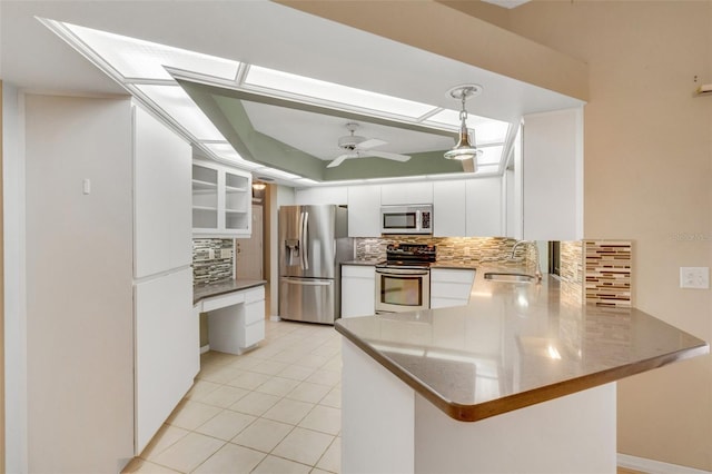 kitchen with light tile patterned floors, appliances with stainless steel finishes, white cabinetry, a sink, and a peninsula