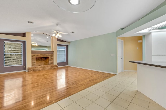 unfurnished living room with visible vents, a ceiling fan, lofted ceiling, light wood-style floors, and a fireplace