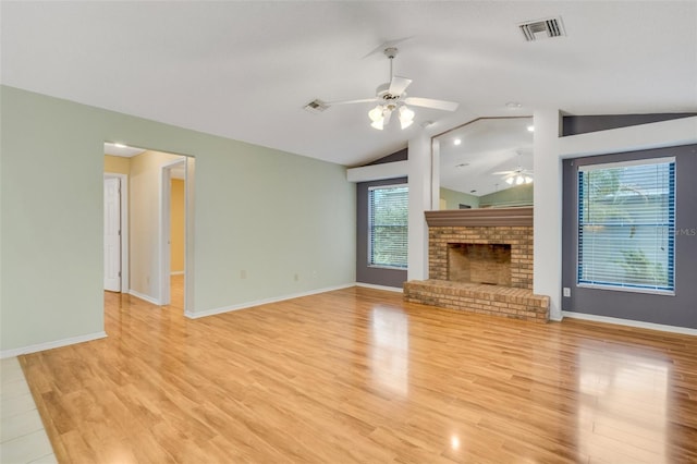 unfurnished living room featuring a brick fireplace, visible vents, vaulted ceiling, and light wood-style floors