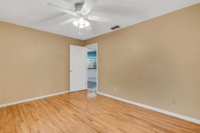 spare room featuring visible vents, ceiling fan, light wood-style flooring, and baseboards