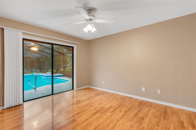 empty room with light wood-style flooring, baseboards, and a textured ceiling