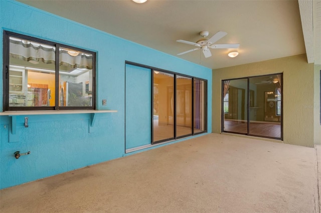 interior space with ceiling fan and a textured wall