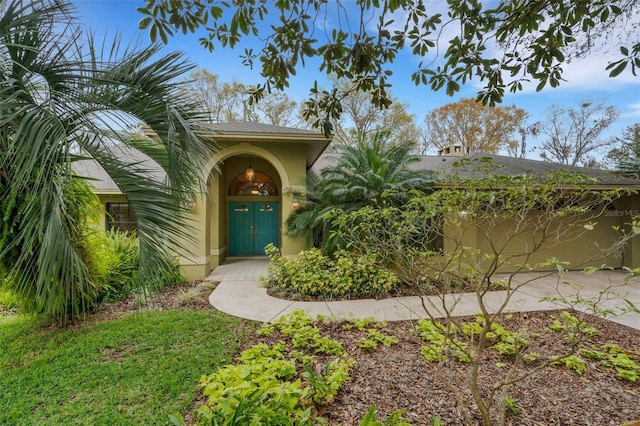 view of exterior entry featuring an attached garage and stucco siding