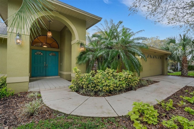 property entrance with a garage, concrete driveway, and stucco siding