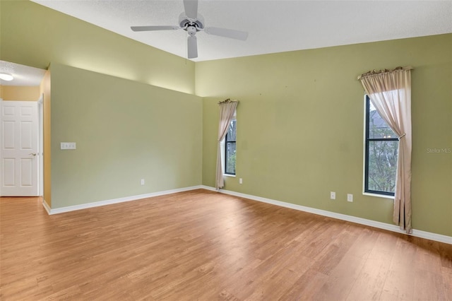 empty room featuring baseboards, ceiling fan, and light wood-style floors